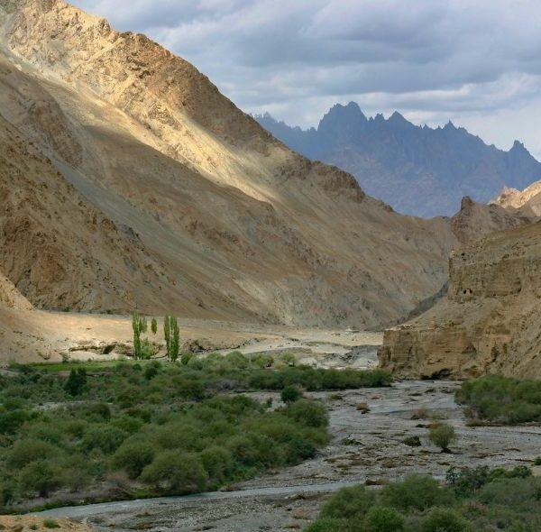 Scenic landscape of Markha Valley Trail, with mountains, river, and blue sky