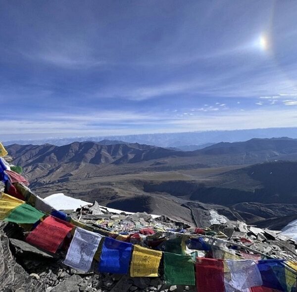 Buddhist Flag waving proudly at the Summit of Kangyatse 2 with a breathtaking view of Kangyatse 1 Peak.