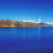 Crystal-clear blue waters of Pangong Lake surrounded by mountains during summer.