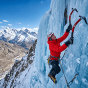 A professional ice climber uses technical axes and crampons to ascend a vertical blue ice waterfall in the mountains of Ladakh.